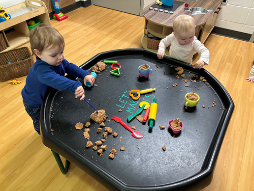 Two children engaged with playdough in the tuff-tray.