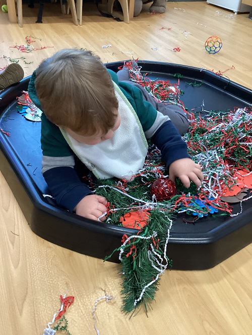 A child exploring with items from the tuff tray.