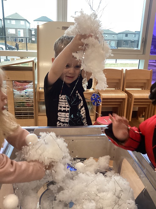 A child holding up items from sensory bin.