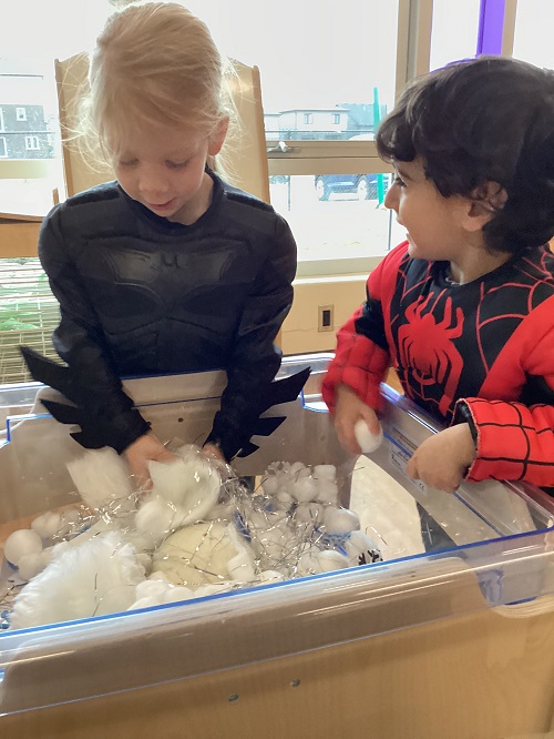 Two children investigating items in the sensory bin.
