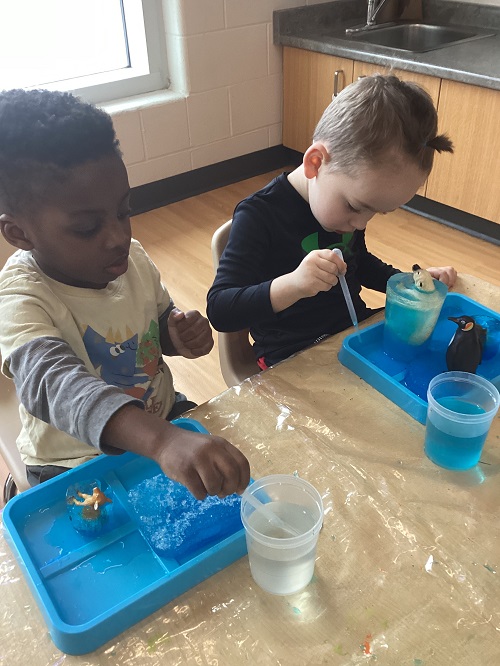 Two children working to free their frozen treasures