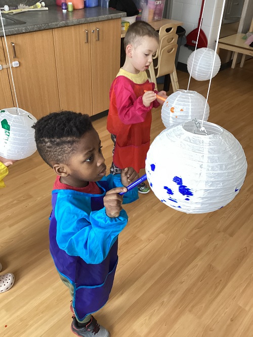 Two children painting suspended lanterns.