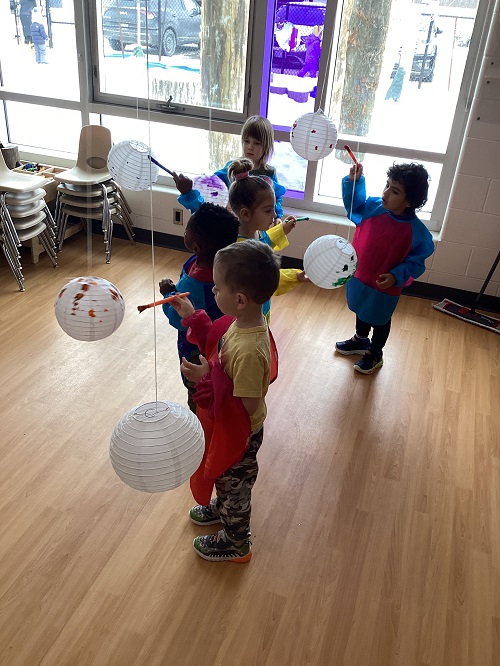 A small group of children painting suspended lanterns.
