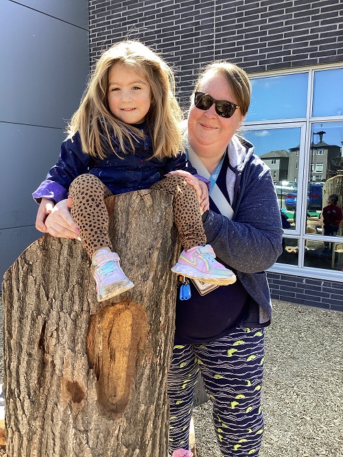 A child sitting on a post with an educator assisting