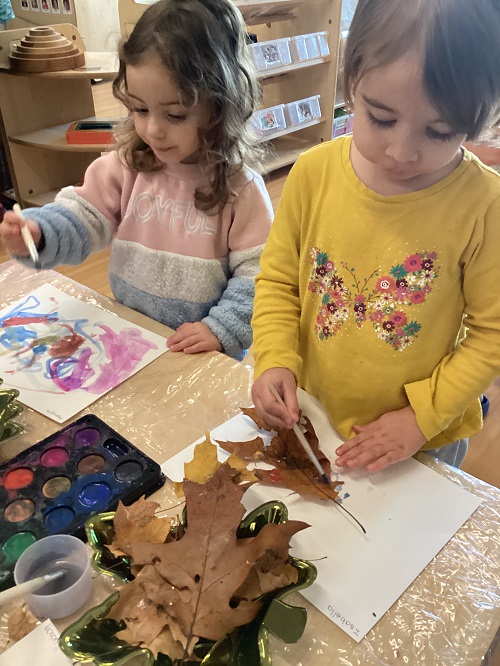 Two children exploring with art materials and fall loose parts.