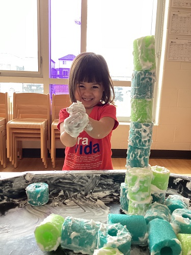 A child manipulating shaving cream in their hands.
