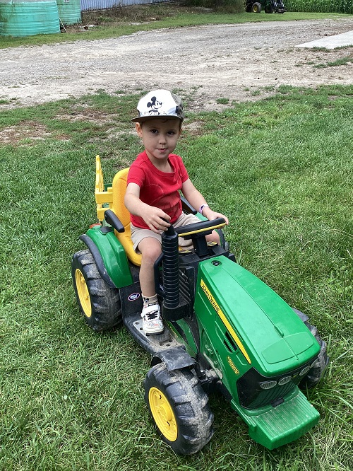 A child sitting on a small tractor.