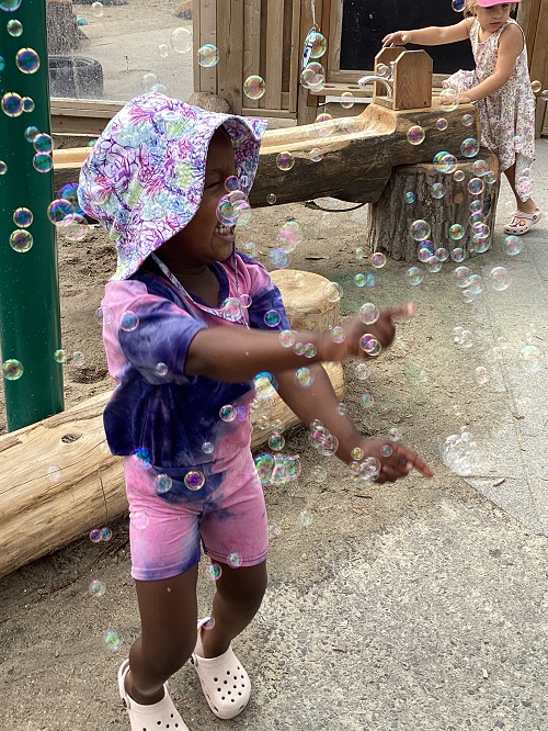 A child on the playground exploring with bubbles.