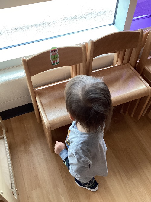A child observing an elf posted on a chair.