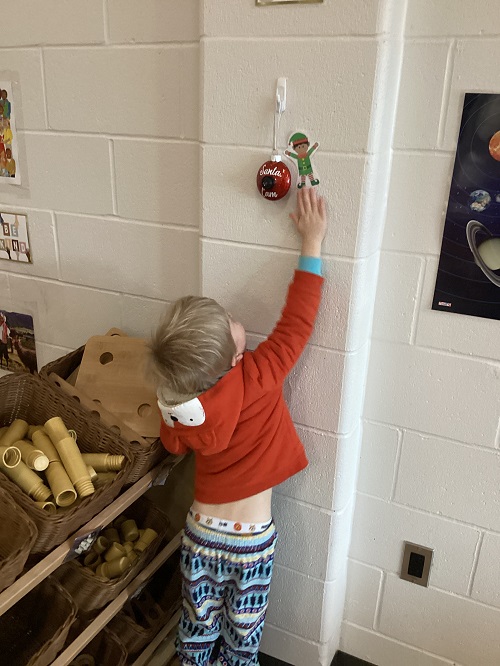 A child pointing at an elf posted on the wall.