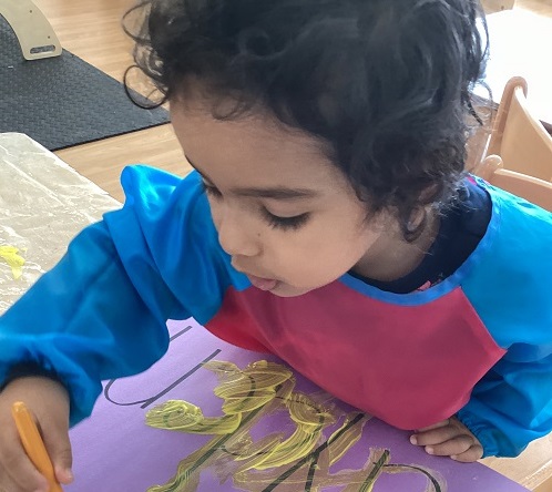 A child painting and tracing over their name