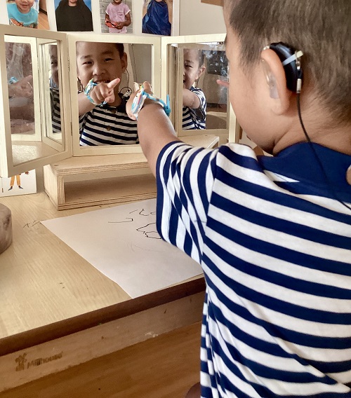 A child pointing at themselves in the mirror.