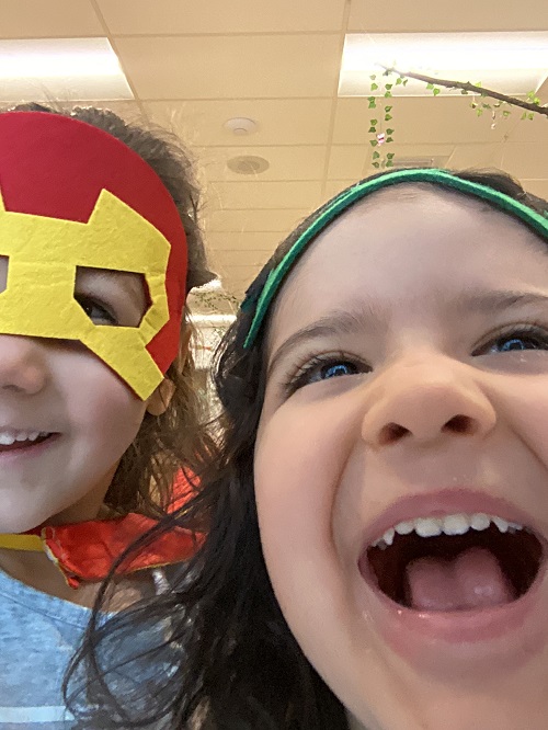 Two children dressed as superheroes taking a selfie together.