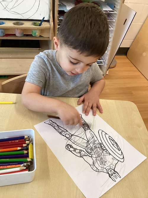 A child colouring a picture of a superhero.