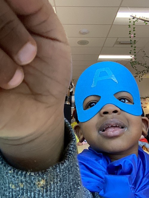 A child dressed up as a superhero taking a selfie.