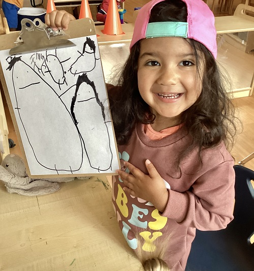 A child smiling while sharing their picture of their family