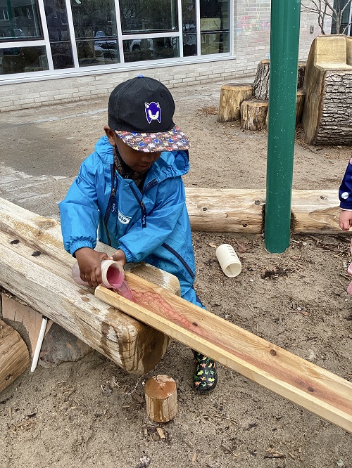 A child pouring a container of water down a ramp.