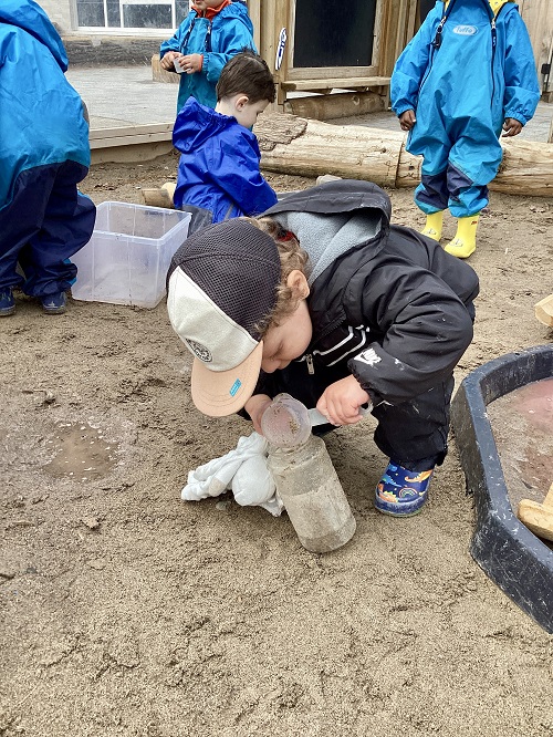 A child pouring water from a scoop into a container.