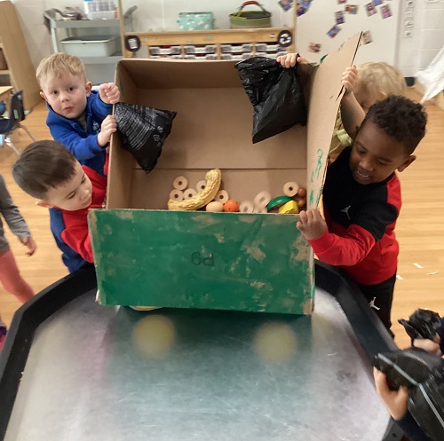 Children pretending to dump garbage out of their garbage truck they created.,