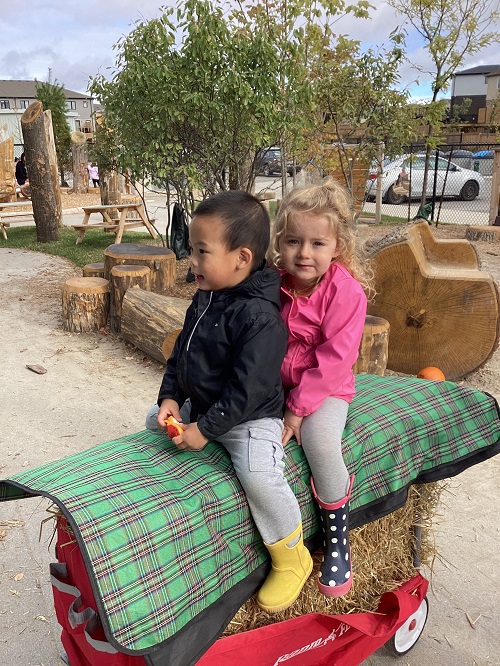 Two children sitting on a wagon for a hay ride.