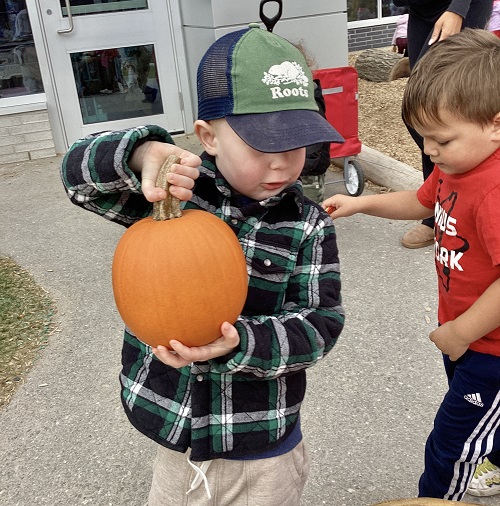 A child holding up a pumpkin.