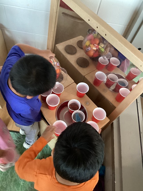 Two children exploring with water while in the dramatic play center.