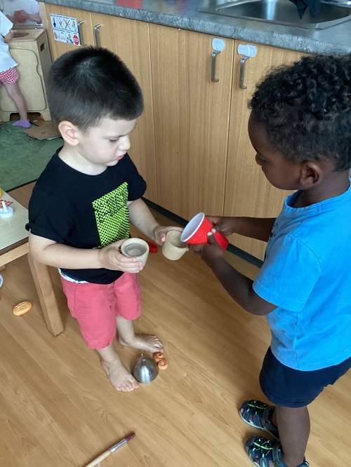 Two children scooping water back and forth with cups.