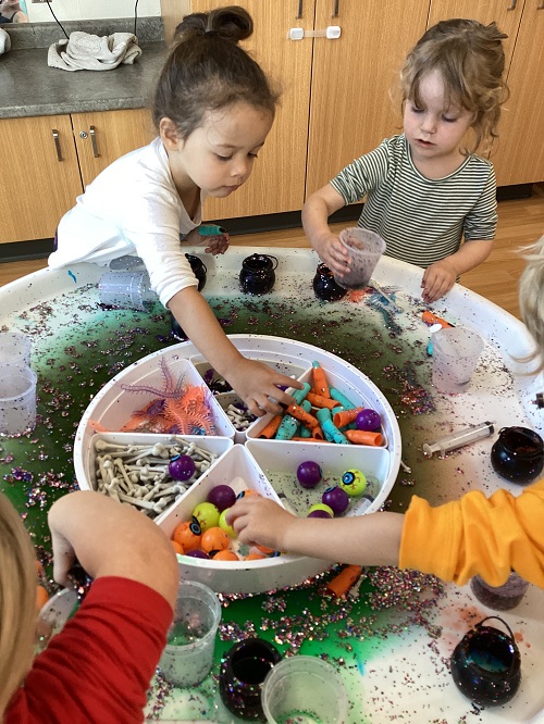 Children exploring with cups of vinegar, baking soda and loose parts.