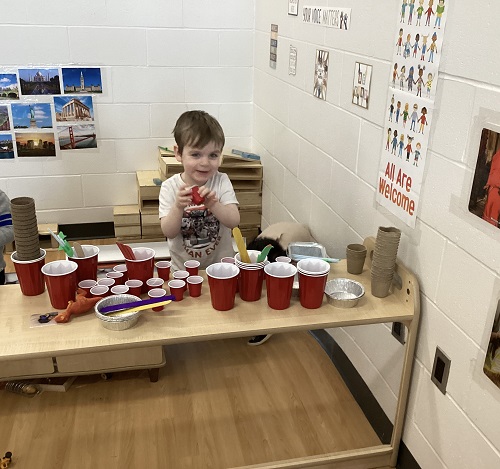 A child standing in front of an arrangement of cups.