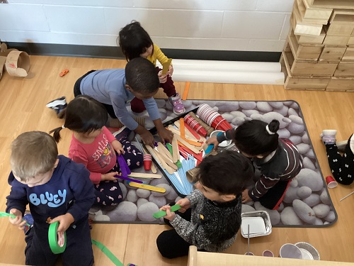 Children sitting on the carpet working with building materials.
