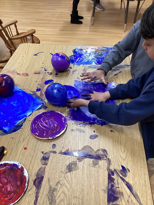 Children exploring with balloons and paint.