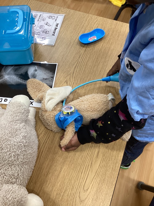 A child is checking the blood pressure on a bunny stuffy.