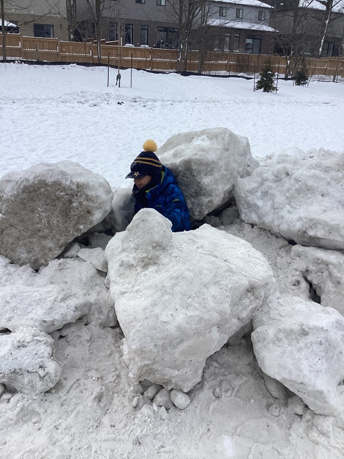 A child sitting on a large snow hill