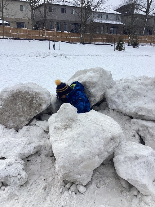 A child sitting on a large snow hill