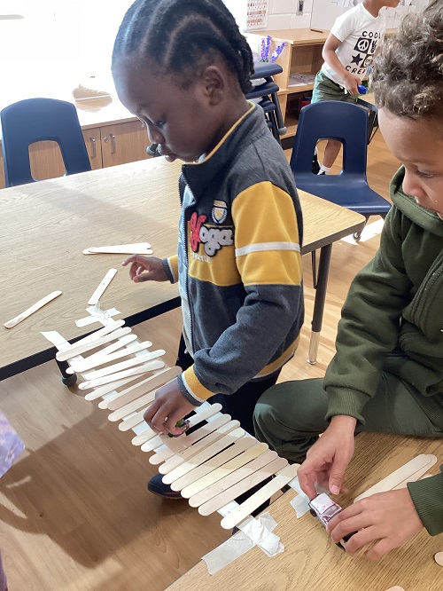 School age children making a popsicle stick bridge