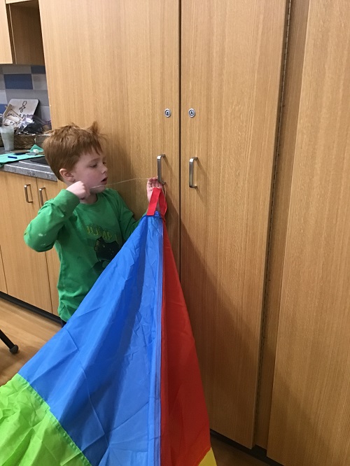 A child tying a parachute to a cabinet door handle