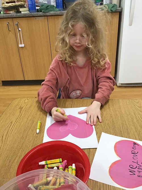 A child creating art inspired by Pink Shirt Day.