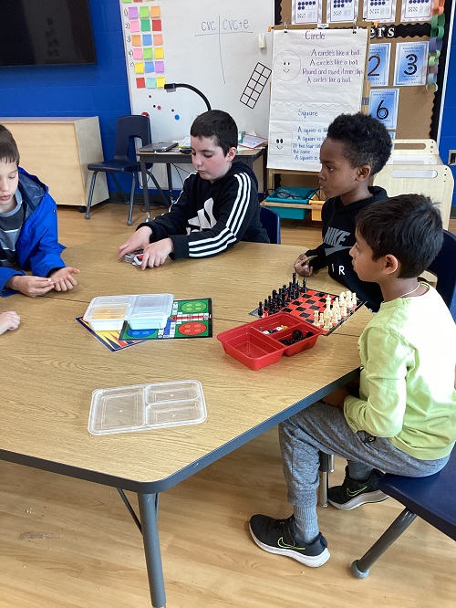 A small group of children sitting at a table getting ready to play chess