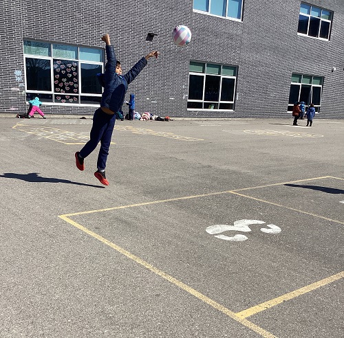 A child throwing a ball while on the playground.