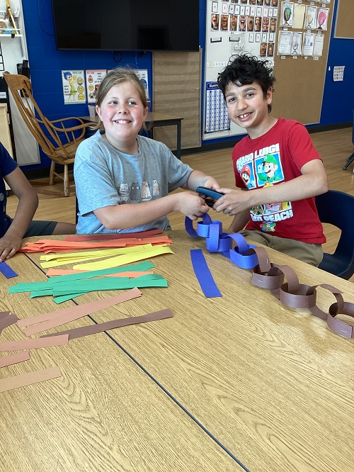 2 children working together to create a rainbow chain.