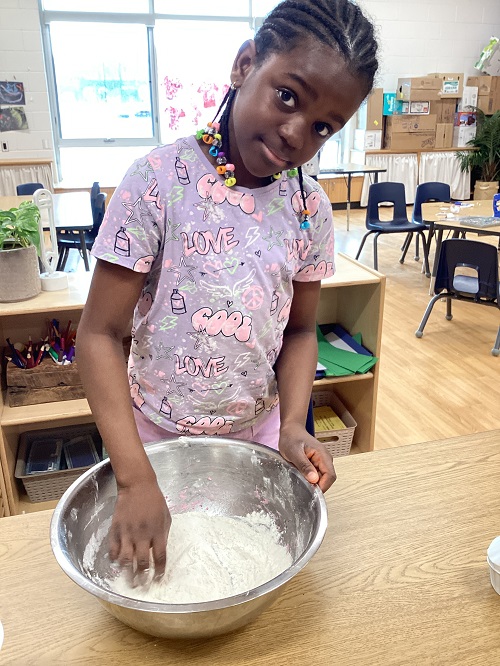 A child beginning to mix playdough in a bowl.