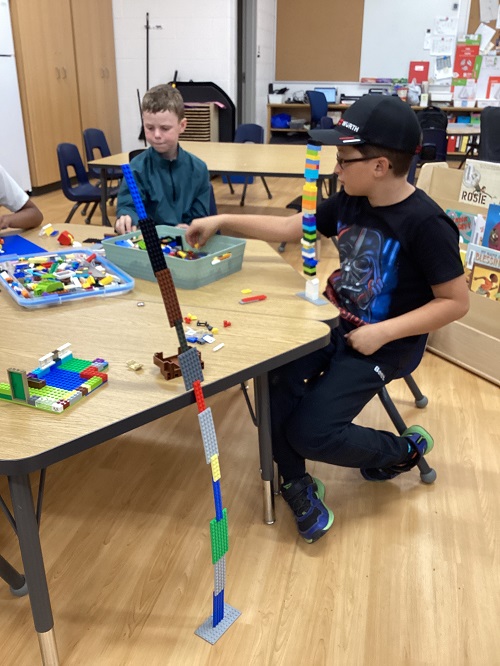 Two children sitting at a table building with lego.