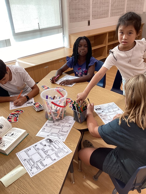 A small group of children writing at a table.