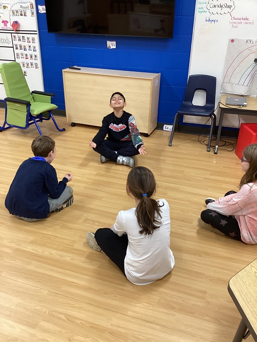 A small group of children sitting in a circle while meditating.