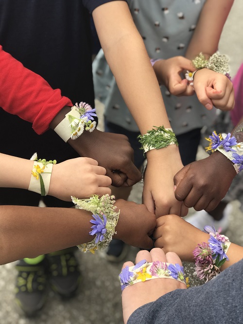 A group of children displaying the nature bracelets they made.