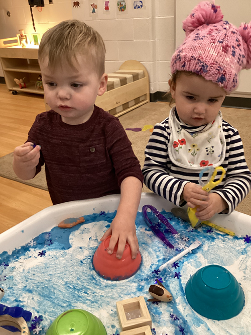 Two children engaging with items in the Arctic tuff-tray.