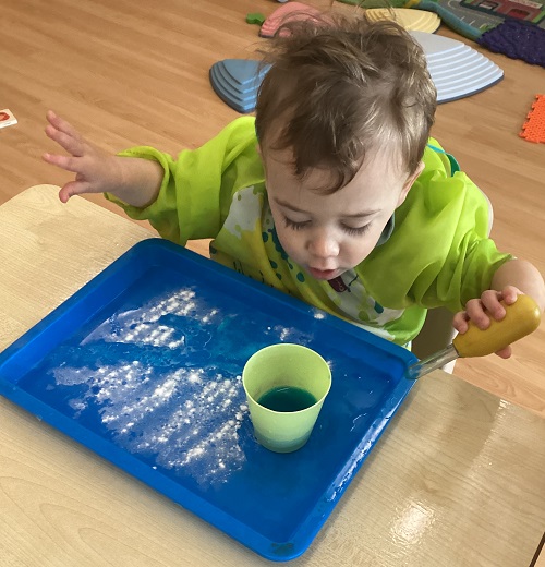 A child looking into their cup of coloured vinegar.