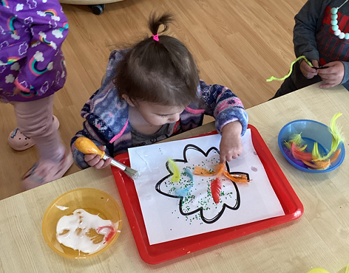 A child applying feathers to their leaf.