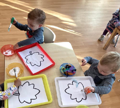 Two children applying glue and feathers to their leaves.