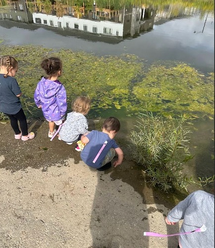 A small group of children observing a pond.
